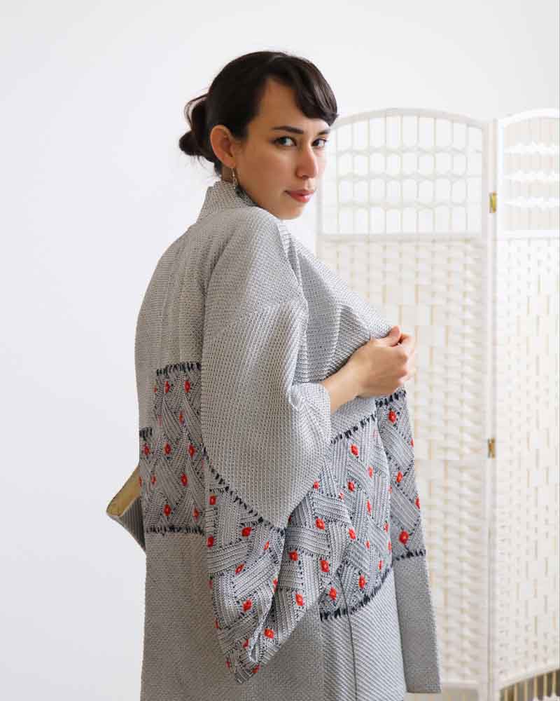 A woman wearing a  blue and gray kimono, facing backwards.