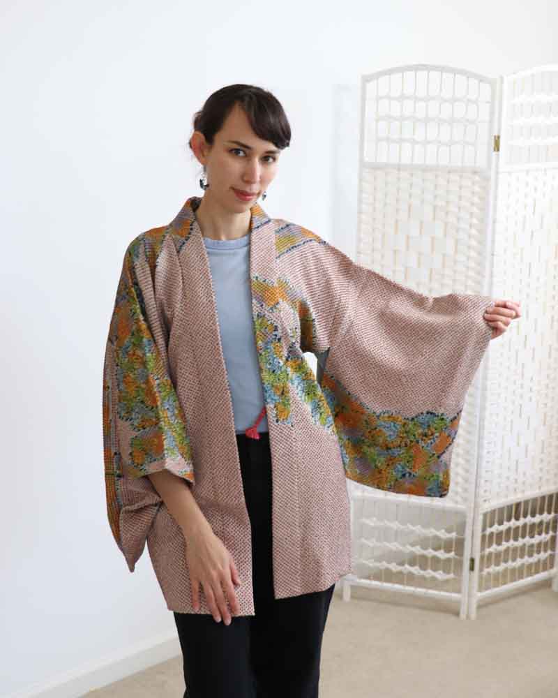 A woman wearing a multi colors kimono, facing forward.