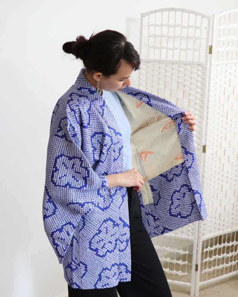 Woman holding a blue patterned jacket with a white background