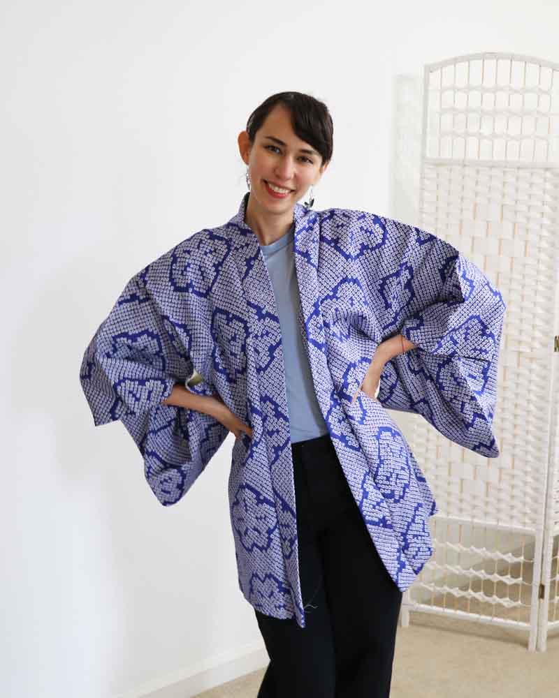 Woman wearing a blue patterned kimono-style garment indoors.