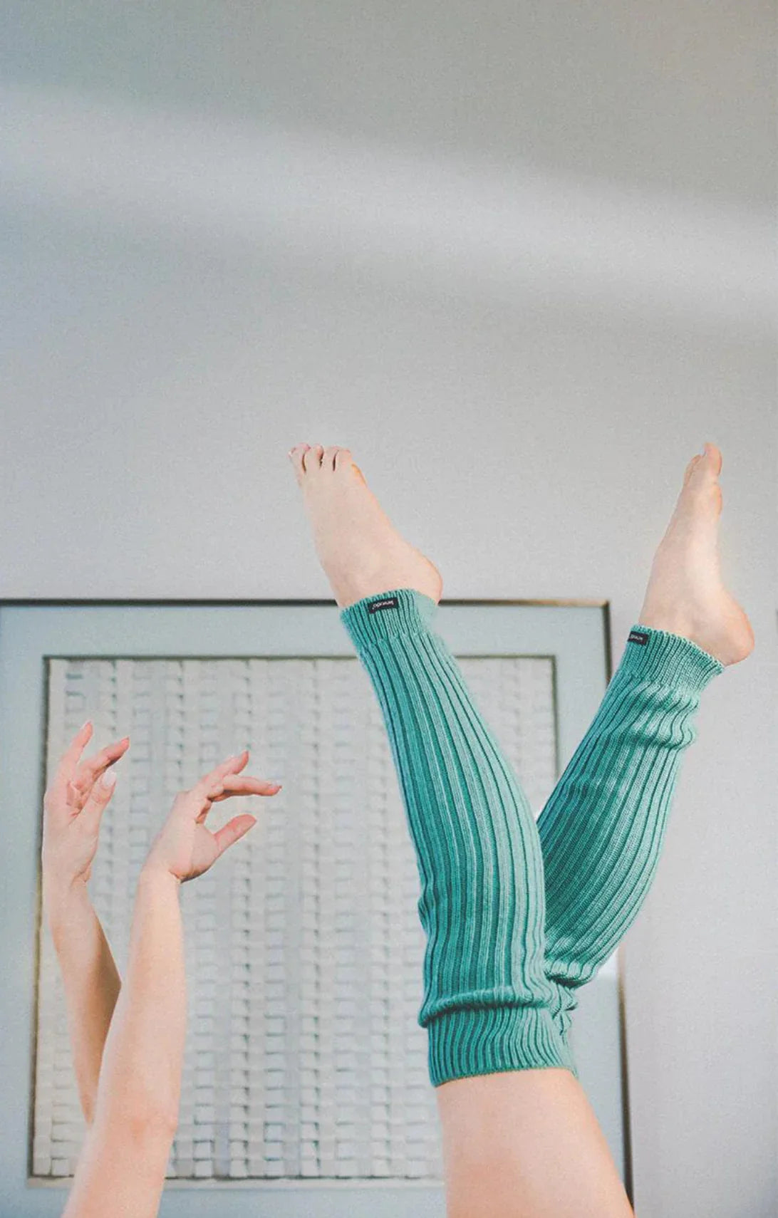 A woman wearing a Knitido plus brand Wool Blend Ribbed Leg Warmer in MINT color is doing ballet.