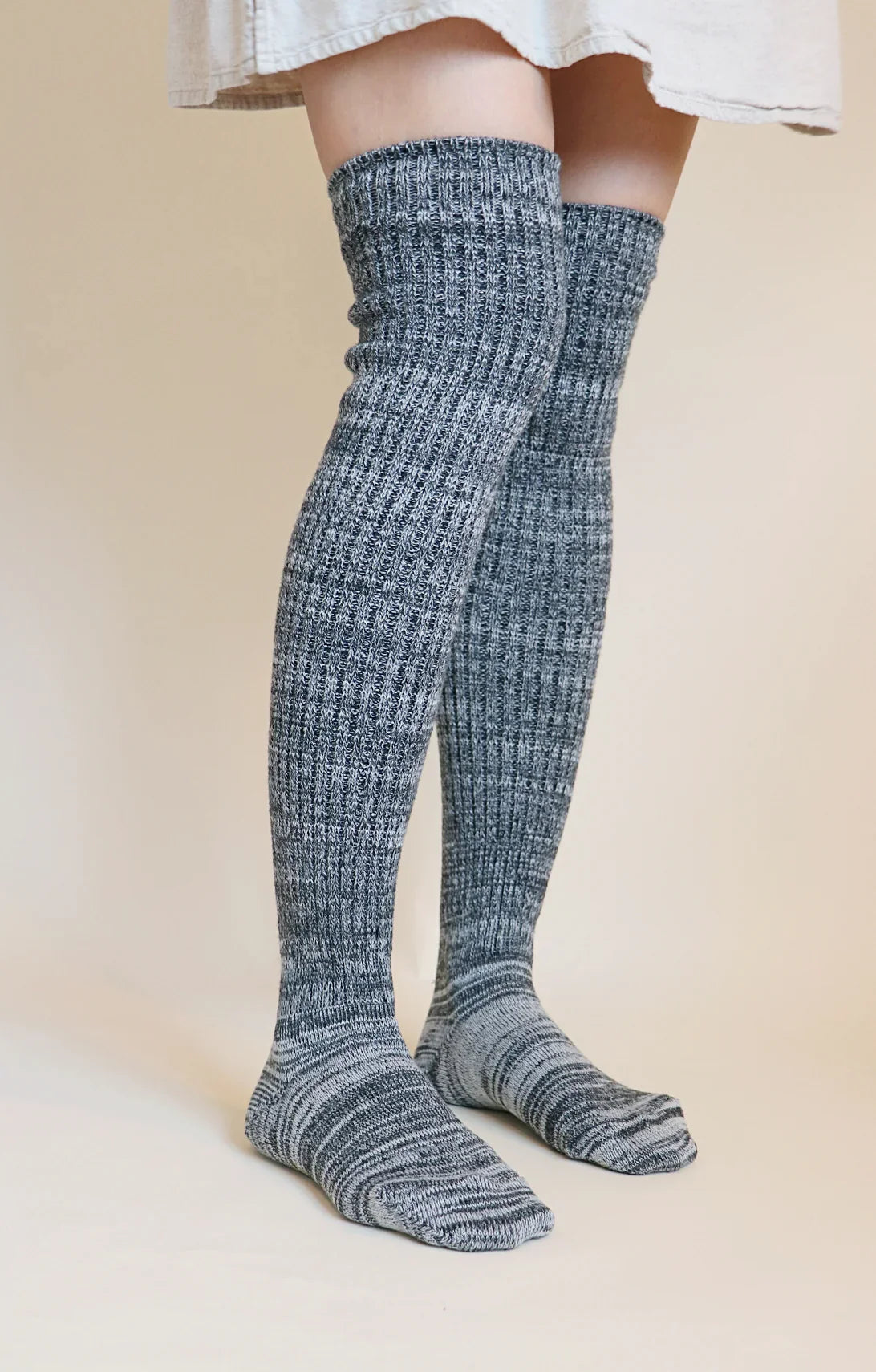 This is a photo of a woman's leg wearing Tabbisocks' product name Scrunchy Over The Knee Lounge Wool Blend Socks Black White Heather