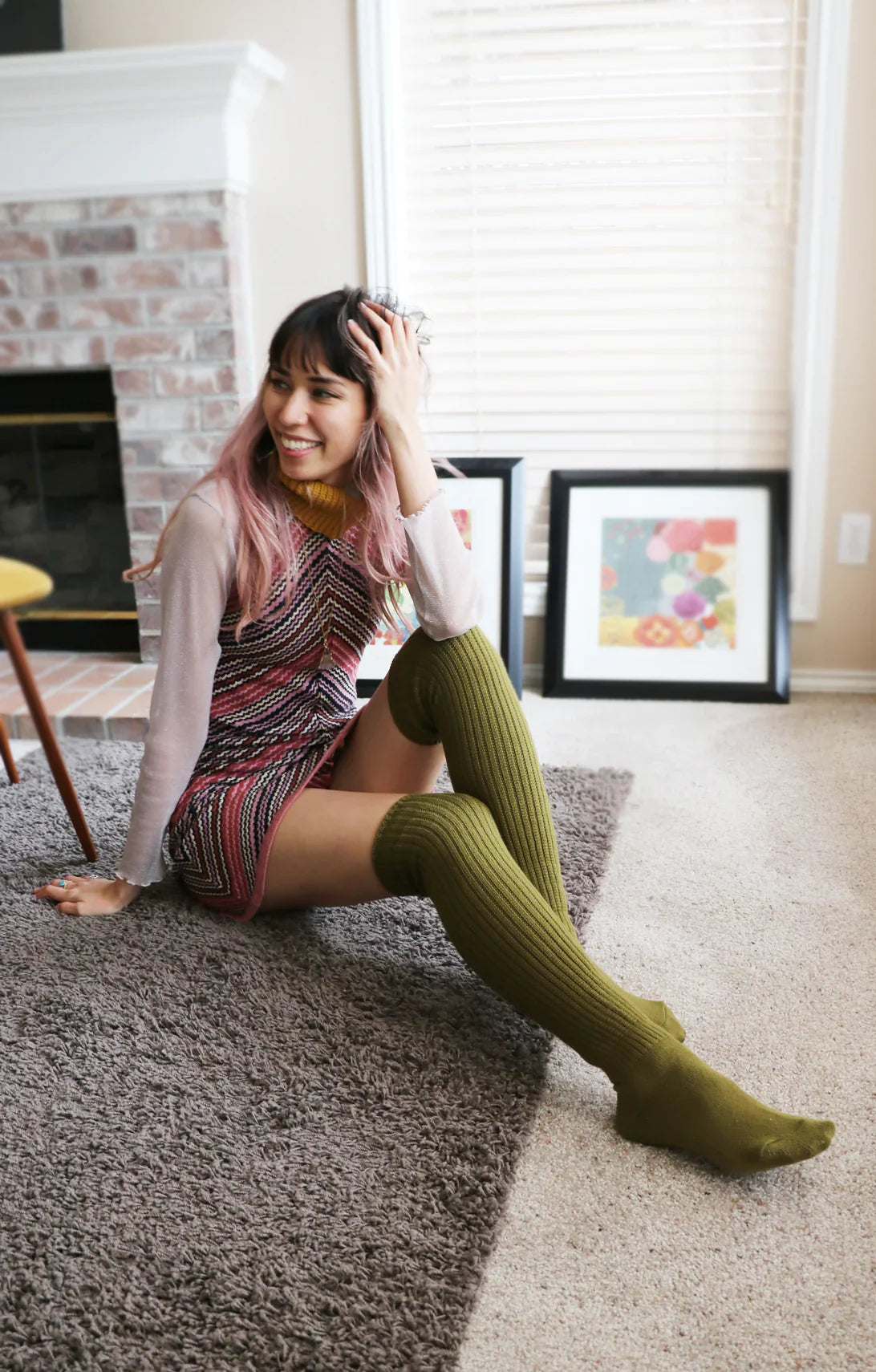 This is a photo of a woman relaxing in her stylish room wearing Tabbisocks' trade name Scrunchy Over The Knee Lounge Wool Blend Socks