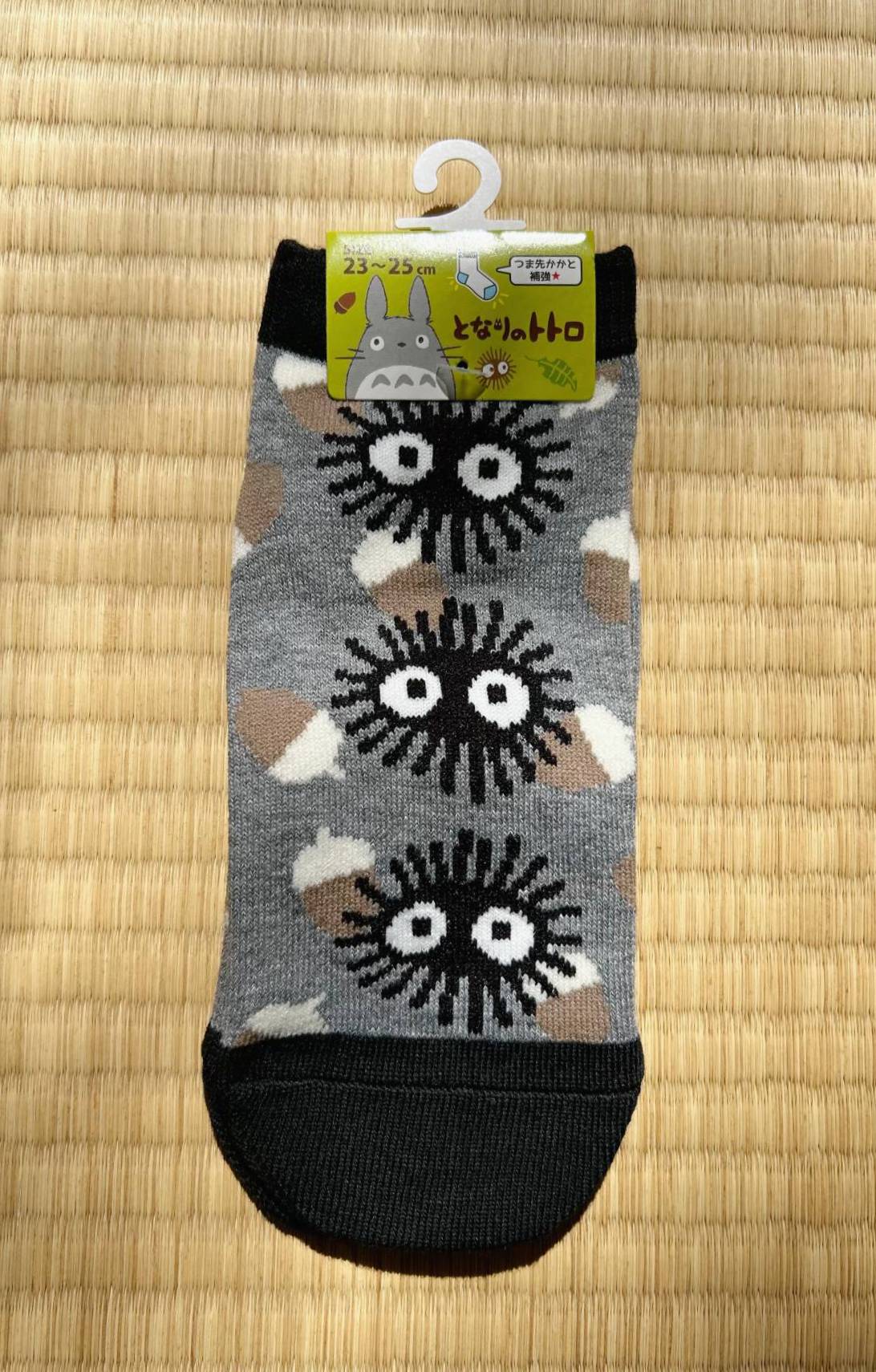 Pair of socks with cartoon character design on a hanger against a straw mat background