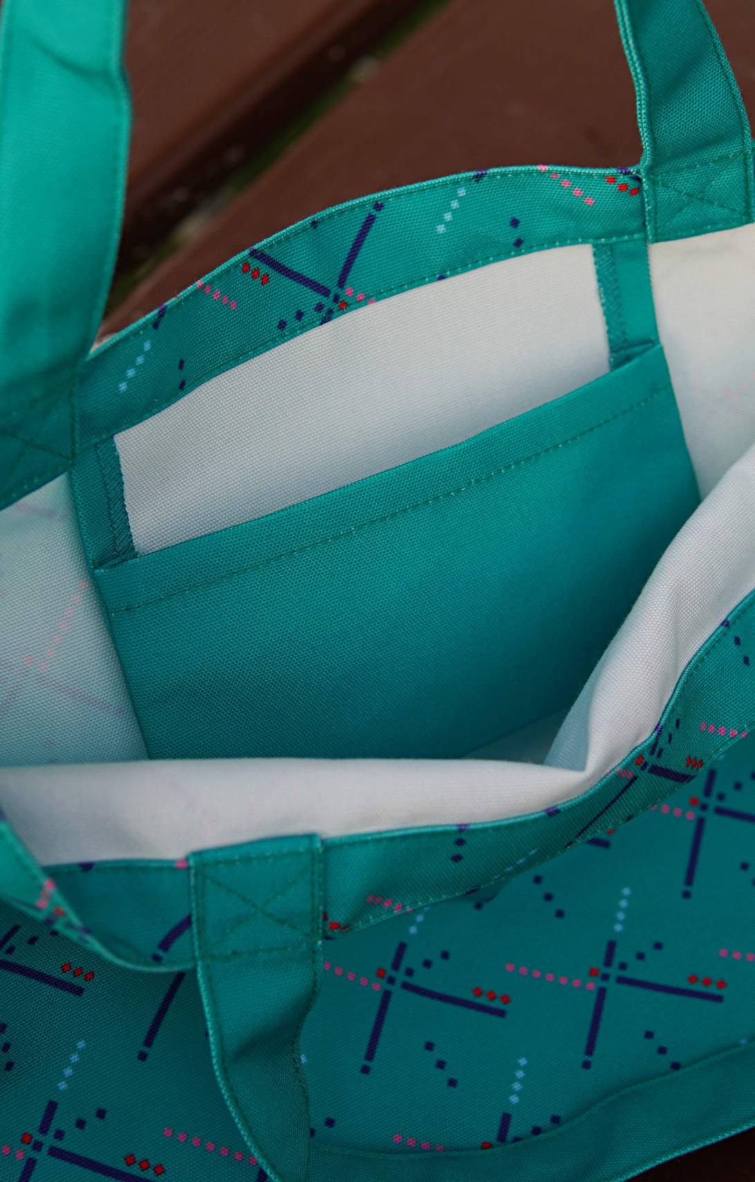 Close-up of a teal tote bag with a patterned interior.